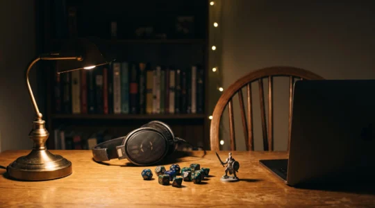 Ambiance chaleureuse d'une session de jeu de rôle à distance, casque audio et dés sur un bureau faiblement éclairé